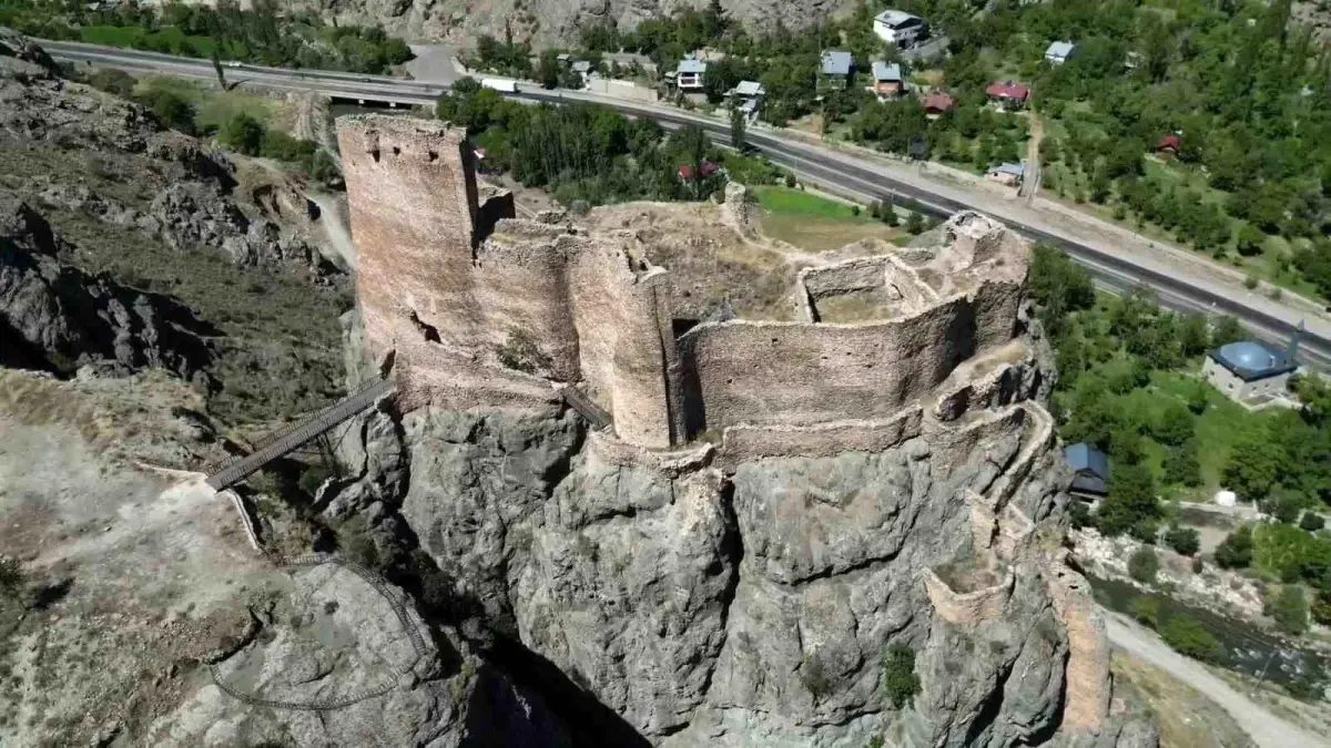 Engüzekkapı Kalesi’nin kayalık üzerindeki surları, havadan; arkada vadi ve yol